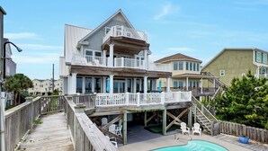 A two-story house with a wooden deck, a pool, and a balcony. - Moondance | Oceanfront | Private Heated Pool & Hot Tub (North Topsail Beach)