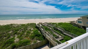 A beach view from a wooden deck with a clear sky. - Moondance | Oceanfront | Private Heated Pool & Hot Tub (North Topsail Beach)