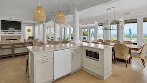 A spacious kitchen with a large island, white cabinetry, and wicker chairs. - Moondance | Oceanfront | Private Heated Pool & Hot Tub (North Topsail Beach)