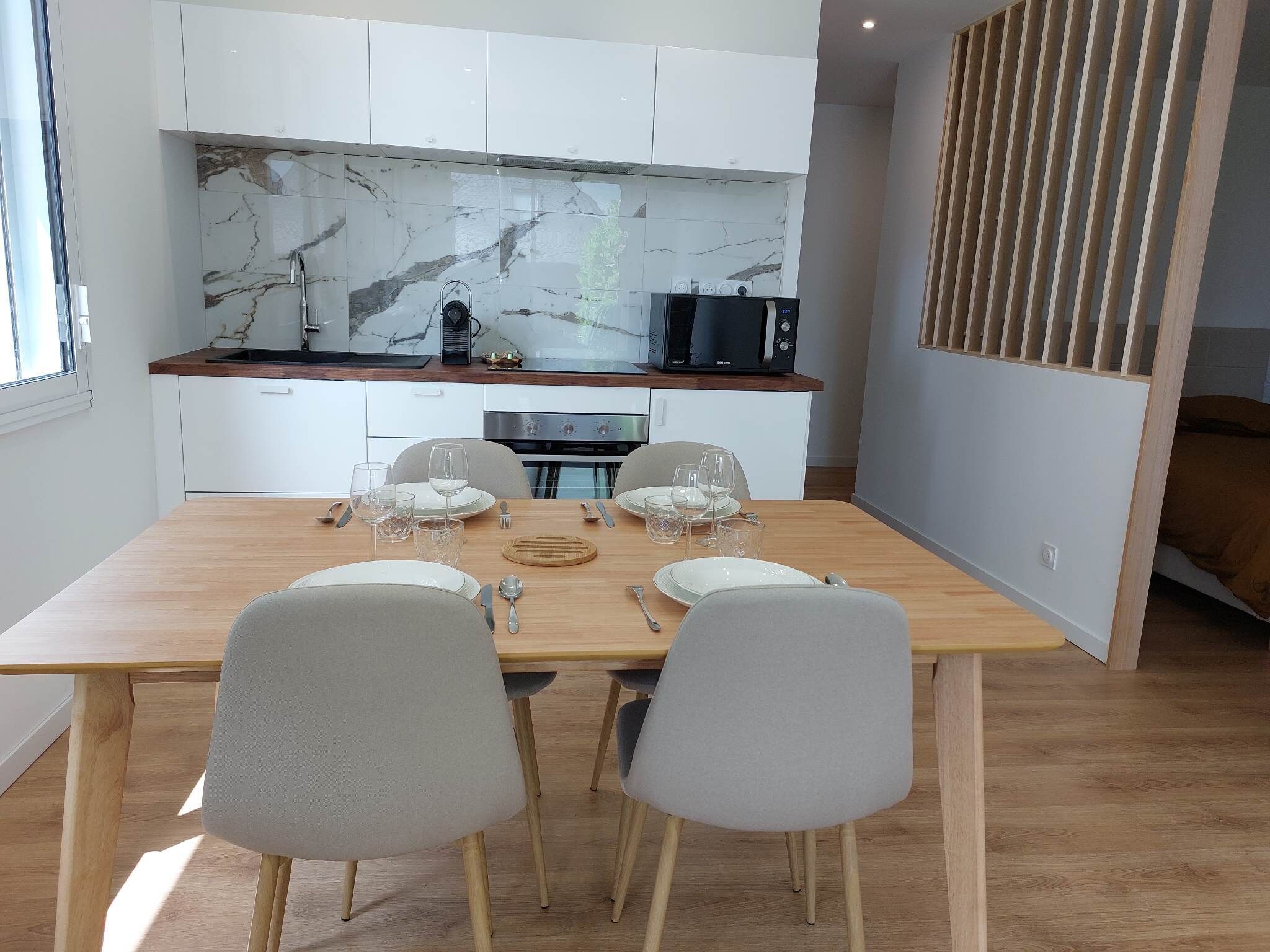 A modern kitchen with white cabinets, a marble backsplash, and a built-in microwave.