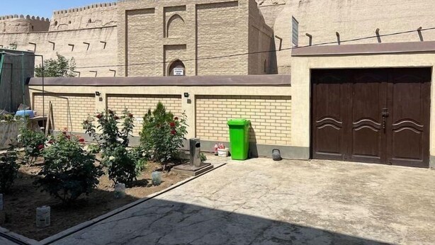 A courtyard with a mosque, a brick wall, and a gate. - Shodlik Guest House (Khiva)