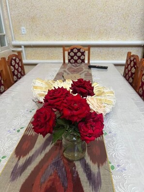 Una mesa de comedor con mantel floral, rodeada de sillas de madera con tapicería floral.