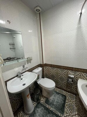 Un baño con lavamanos blanco, inodoro y espejo.
