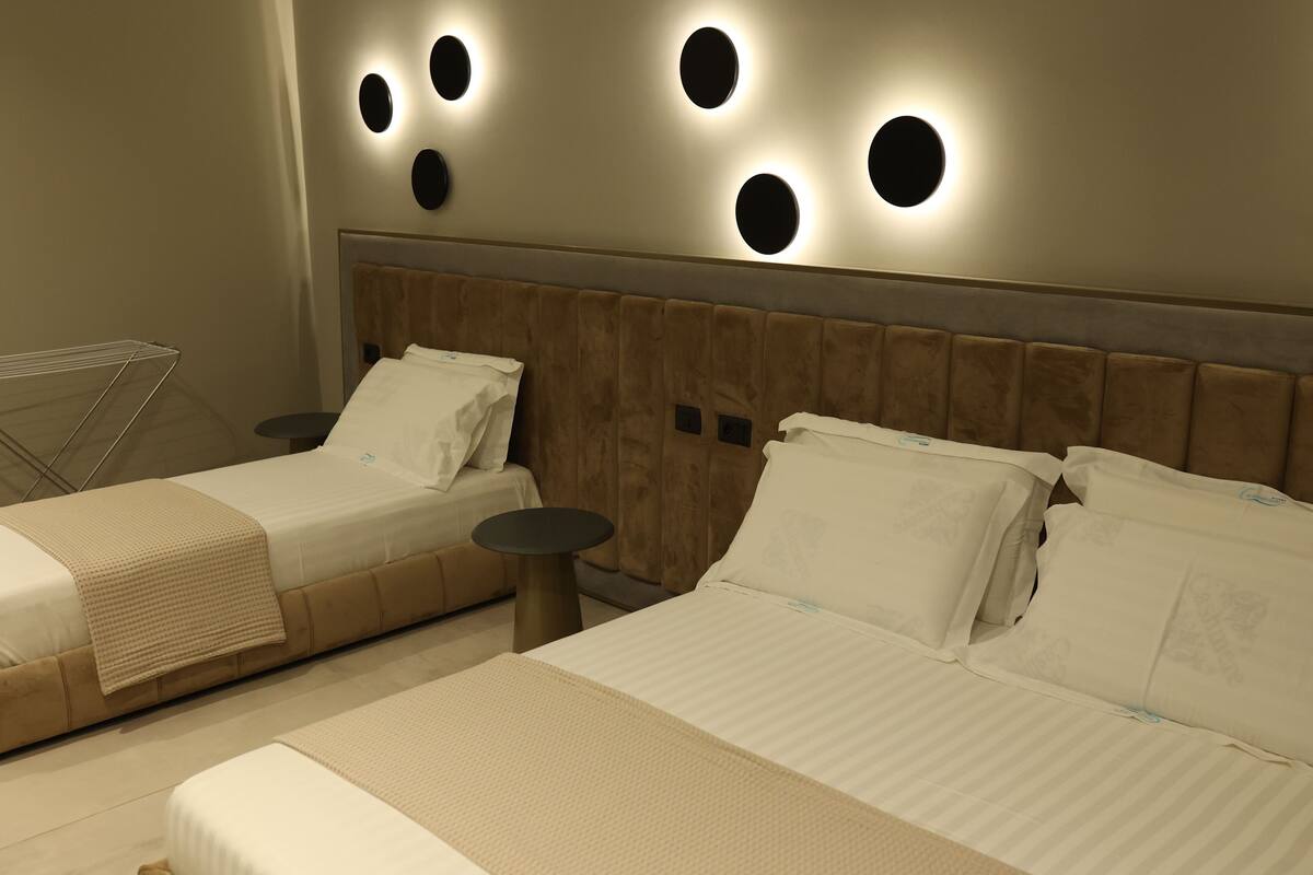Two single beds with headboards, a small round table, and a wall-mounted light fixture.