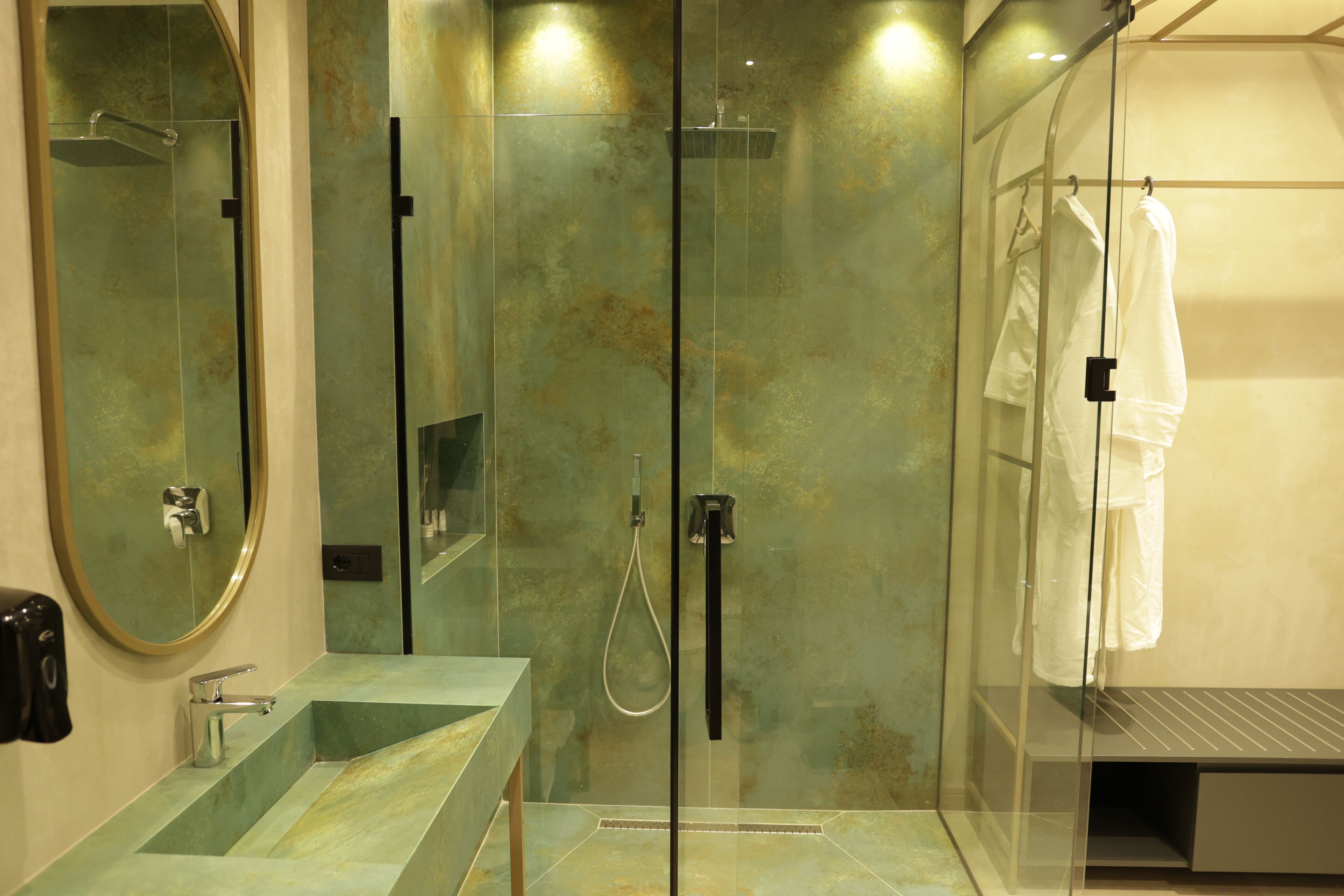 A modern bathroom with a glass-enclosed shower, a sink with a marble countertop, and a mirror with a gold frame.