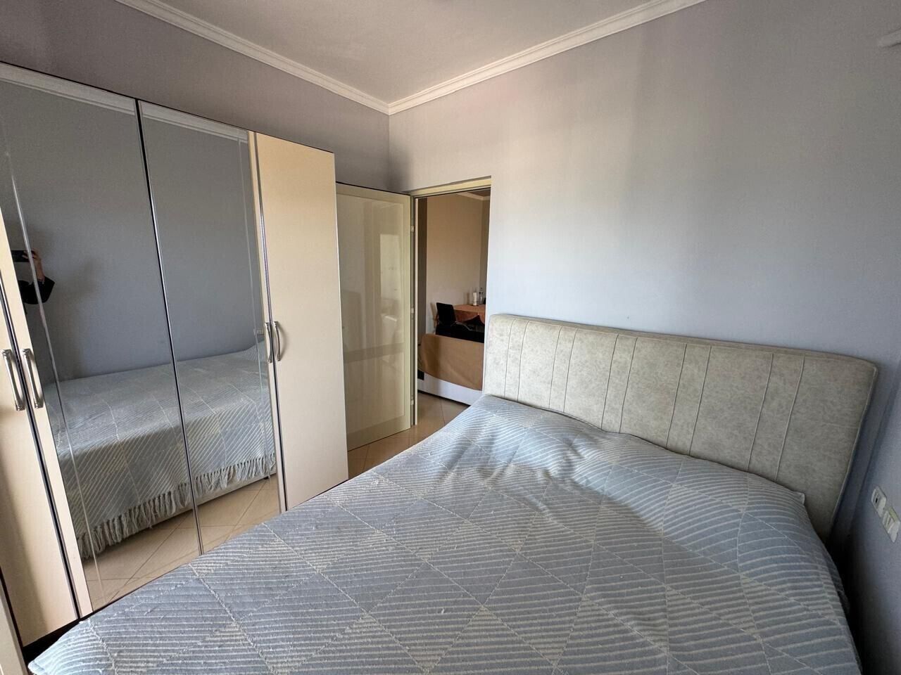 A bedroom with a bed, a wardrobe, and a bathroom visible through an open door.