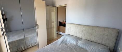 A bedroom with a bed, a wardrobe, and a bathroom visible through an open door.