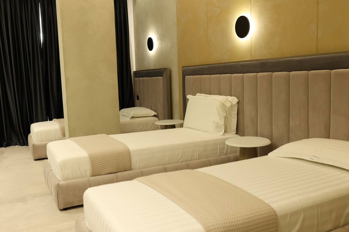 A hotel room with two single beds, a round table, and a small seating area.