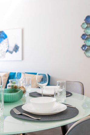 A dining table set with plates, cutlery, and glasses, with a green bowl and decorative items on the side. - Luxury Beachfront Marjan Island (Ras Al Khaimah)