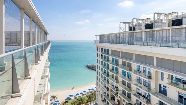 Hotel alto com varanda com vista para uma praia e o mar.