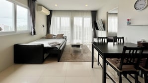 A modern hotel room with a bed, a desk, and a dining table.