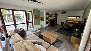 Un salon moderne avec un canapé beige, une table basse en bois et un coin repas comprenant une table et des chaises.