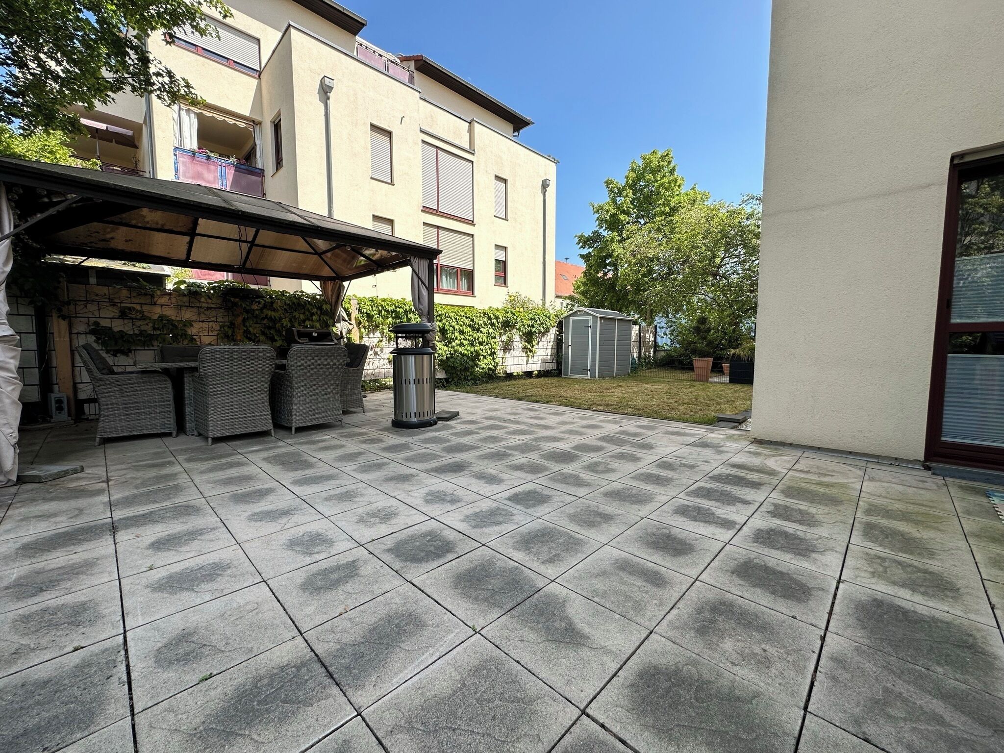 A patio with tiled flooring, outdoor furniture, and a covered seating area.