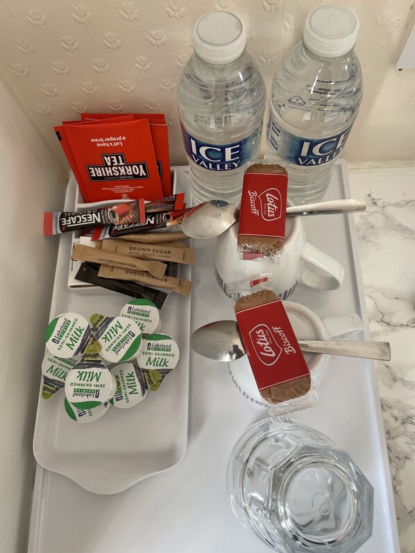 Una bandeja con diferentes alimentos y bebidas, incluyendo botellas de agua de Valle Helado, galletas Lotus y leche semidesnatada Lakeland.