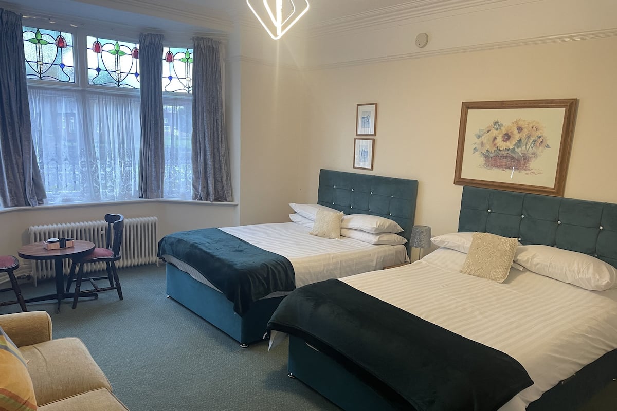 Ein Hotelzimmer mit zwei Betten, einem kleinen Tisch, einem Stuhl und einem Heizkörper.