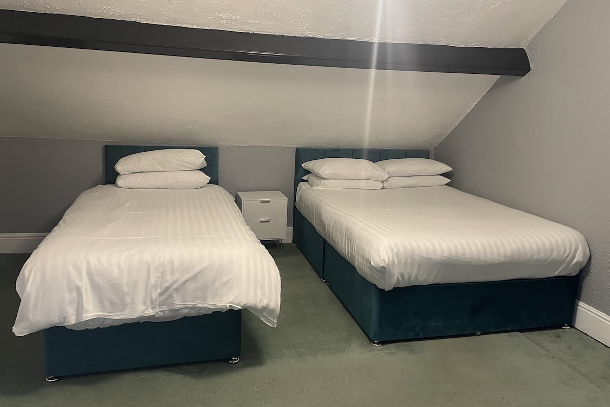 Ein Doppelzimmer mit zwei Einzelbetten, einem Nachttisch und einer Deckenleuchte.