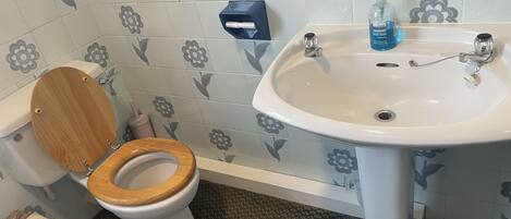 A bathroom with a toilet, sink, and hand sanitizer dispenser.