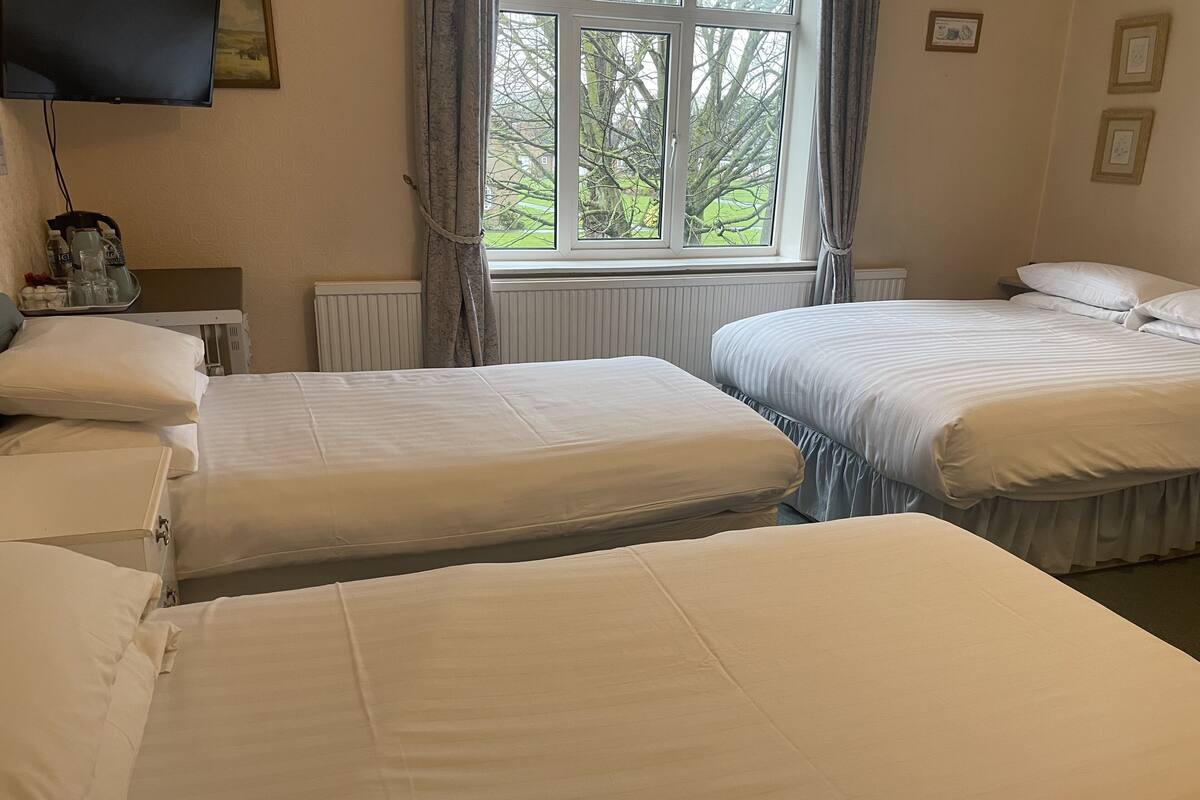 Ein Hotelzimmer mit zwei Betten, einem Fernseher und einem Fenster mit Vorhängen.