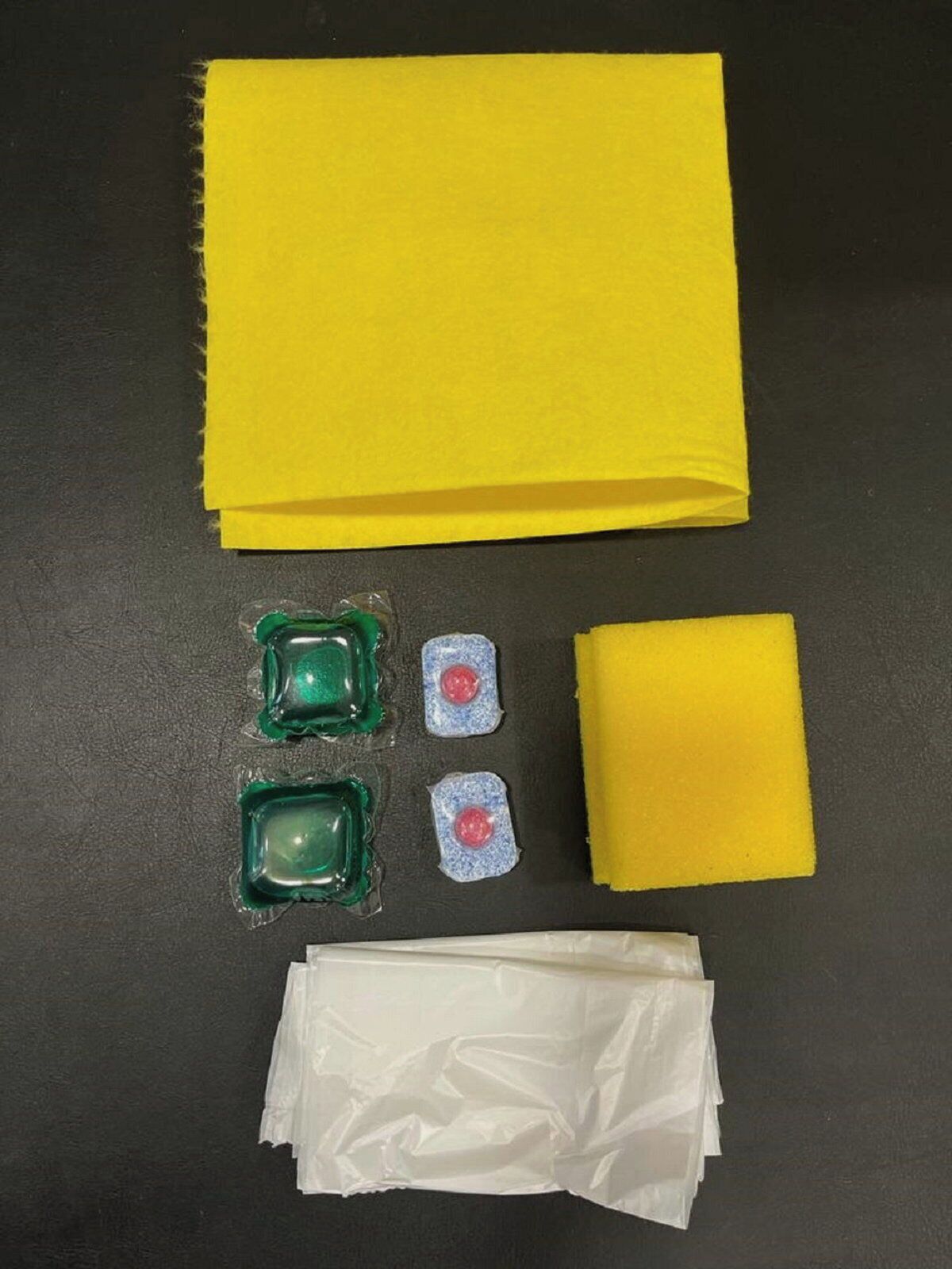 A yellow notebook, a stack of white papers, and three small containers with green and blue lids.