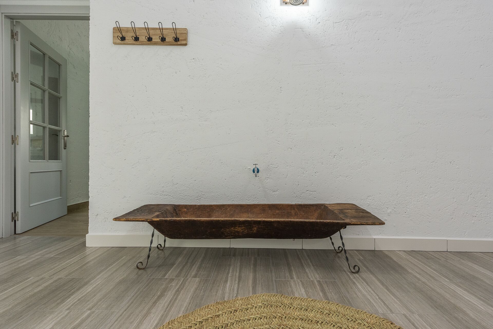 Une pièce avec une baignoire en bois, un porte-manteau en bois et une porte.