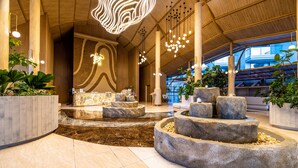 A modern lobby with a central water feature, wooden paneling, and hanging lights. - Phuket Emerald Beach Resort (Karon)
