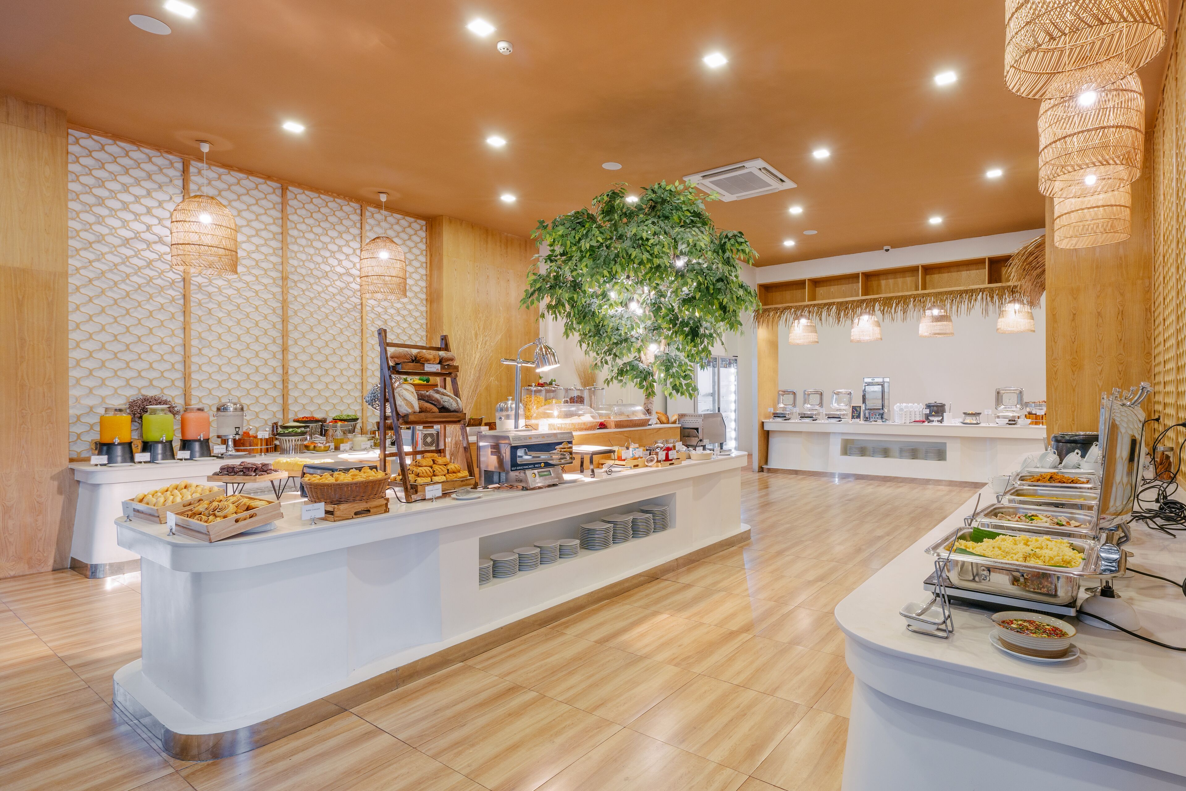 A buffet area with various food stations, a central plant, and a modern interior design.