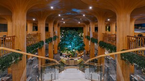 A multi-level atrium with wooden columns, a central tree, and a staircase. - Phuket Emerald Beach Resort (Karon)