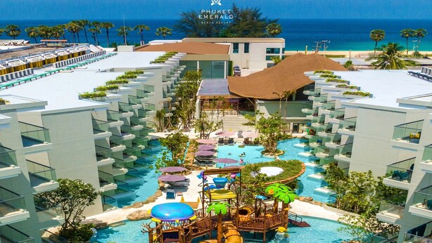 A resort with a large pool area, including a water slide and play structures, surrounded by modern buildings with balconies. - Phuket Emerald Beach Resort (Karon)