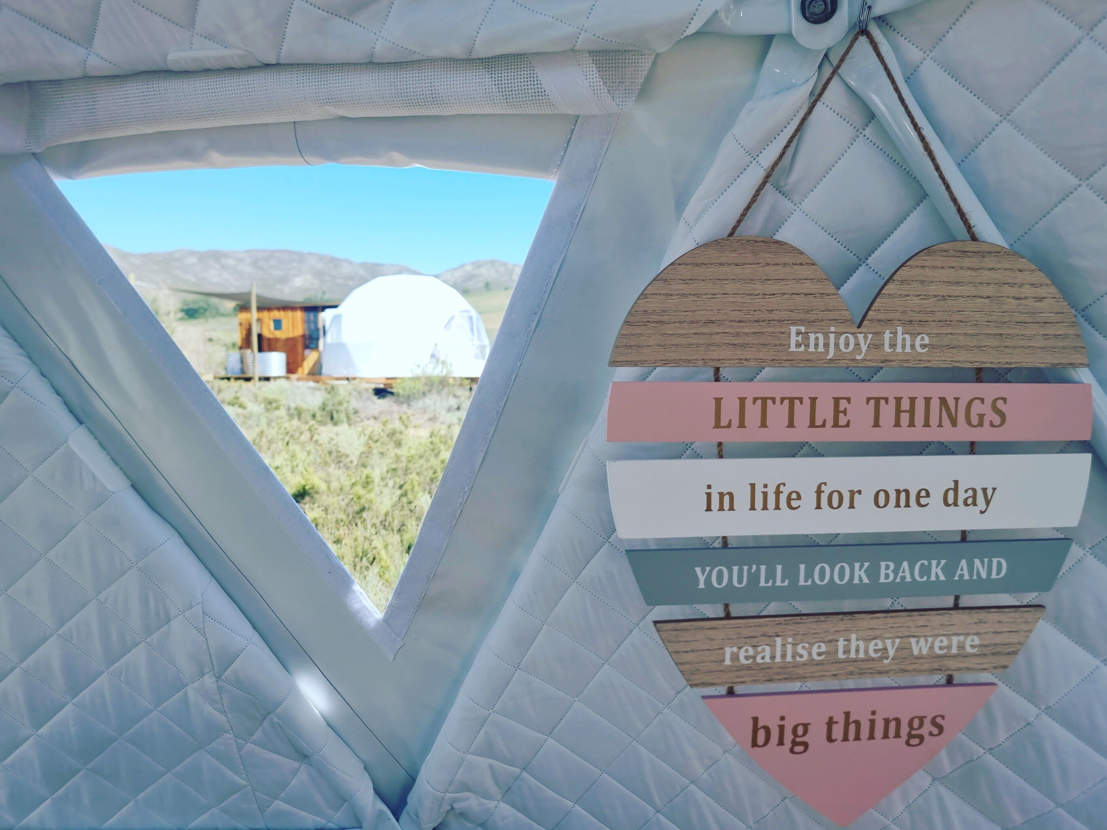 A view from inside a tent with a heart-shaped sign with motivational text.