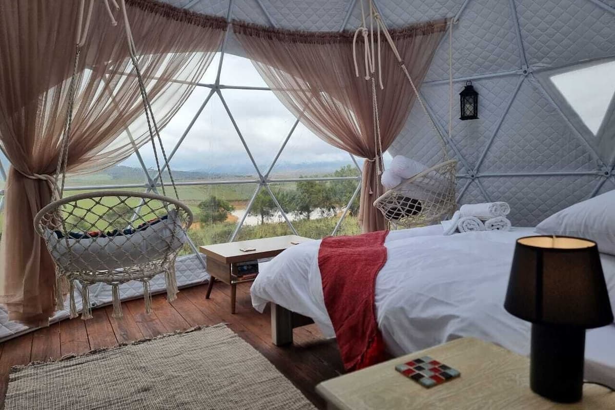 Una habitación acogedora con una cama, una silla y vistas al paisaje.