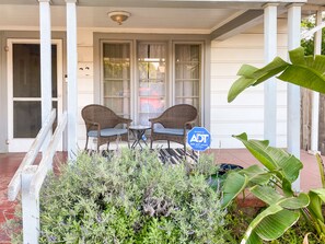 A porch with two wicker chairs and a small table, a security sign, and a variety of plants. - Prime Los Feliz Craftsman 2/1 Bungalow Home, Big Yard, Dog Friendly,Washer/Dryer (Los Angeles)