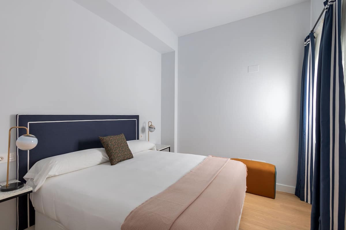 A neatly arranged bedroom with a bed, bedside lamp, and a small nightstand.
