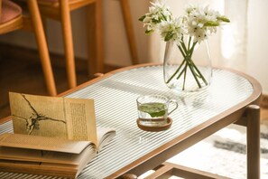 A table with a book, a glass of water, and a vase of flowers.