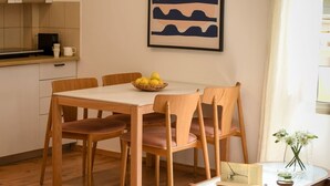 A dining area with a wooden table and chairs, a bowl of lemons, and a framed artwork on the wall. - MAMAD - Pet-friendly 2BR Apt & Kitchen (Tel Aviv)