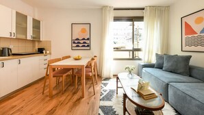 A compact living space with a kitchenette, dining area, and a sofa. - MAMAD - Pet-friendly 2BR Apt & Kitchen (Tel Aviv)