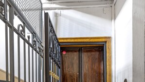 A narrow hallway with a metal gate, a wooden door, and a marble floor. - Irnerio Apartments by Wonderful Italy (Bologna)
