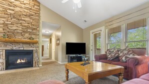 A living room with a stone fireplace, a television, a sofa, and a coffee table.