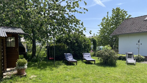 A backyard with two lounge chairs, a swing, and a small shed. - Vacation home Beulskopf - relaxing in nature (Heupelzen)