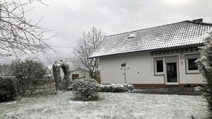 A house with a tiled roof, a small garden, and a snow-covered lawn. - Vacation home Beulskopf - relaxing in nature (Heupelzen)