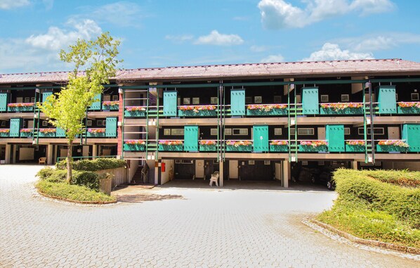 Un hôtel à plusieurs étages doté de balcons, d’un parking couvert et d’une cour dallée.