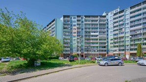 A multi-story residential building with balconies, a paved parking area, and a tree-lined street. - Compact Studio | Close to Park, Pet Friendly (Wroclaw)