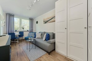 Un salon moderne comprenant un canapé, des fauteuils, une table à manger et une grande fenêtre.
