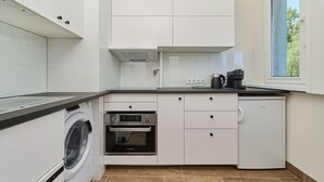 A compact kitchen with a washing machine, oven, and dishwasher. - Compact Studio | Close to Park, Pet Friendly (Wroclaw)