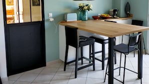 Un comedor con una mesa de madera, sillas negras, un jarrón con flores, un reloj y un espejo colgado en la pared.