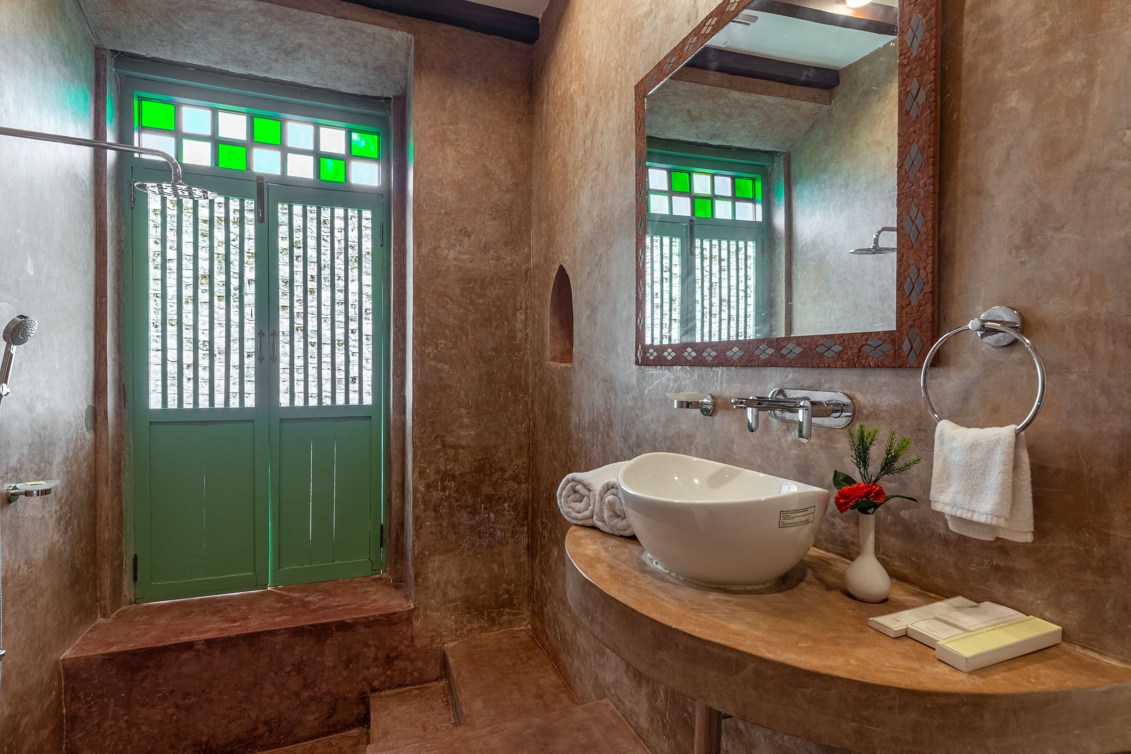A bathroom with a green door, a white sink, a mirror, and a towel rack.