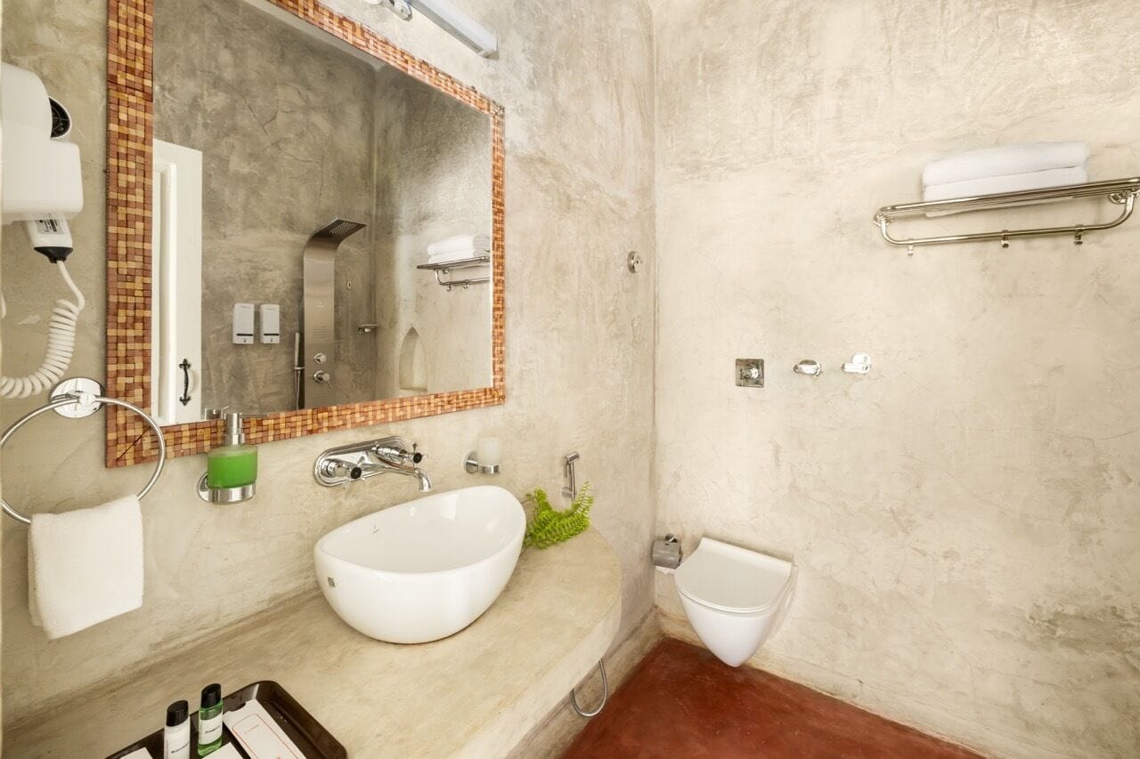 A bathroom with a white sink, a large mirror, a towel rack, a bidet, and a hairdryer.