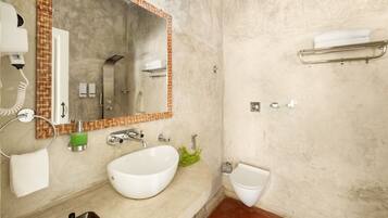 A bathroom with a white sink, a large mirror, a towel rack, a bidet, and a hairdryer.