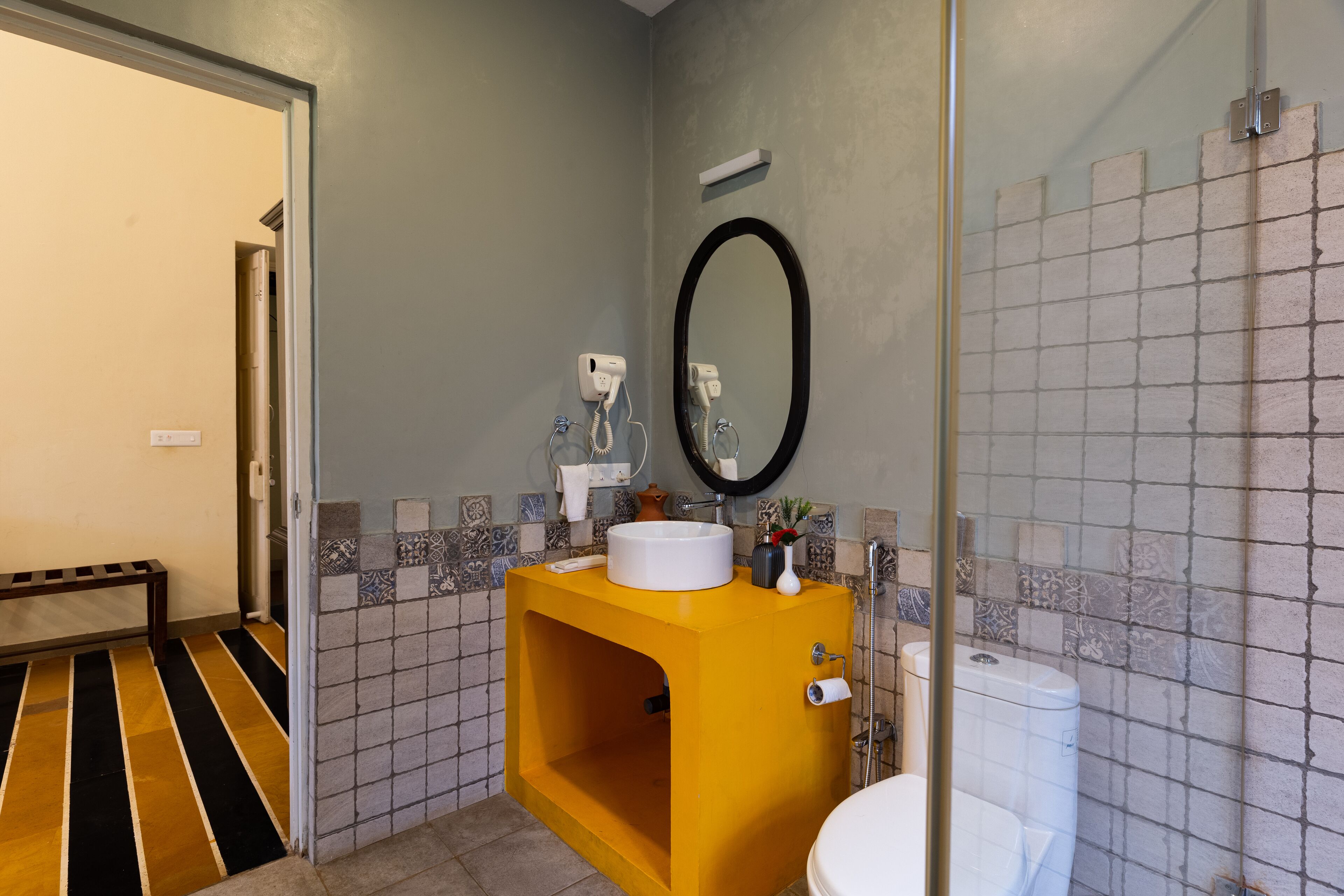 A bathroom with a yellow sink, a white toilet, and a mirror.