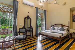 Quarto com cama, cadeira, mesa, espelho e janela com cortinas.