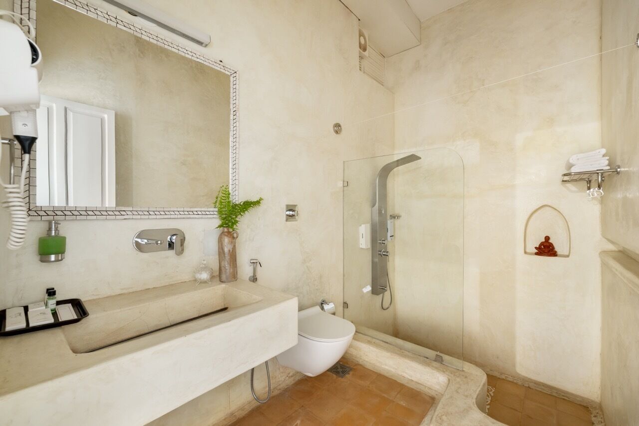 Une salle de bain moderne avec un grand miroir, un lavabo, des toilettes et une douche séparée par une paroi de verre.